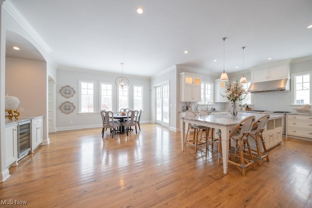 dining room featuring wine cooler, plenty of natural light, and ornamental molding