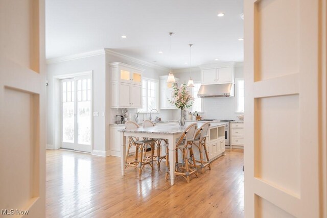 kitchen with ventilation hood, a kitchen island, white cabinetry, and tasteful backsplash