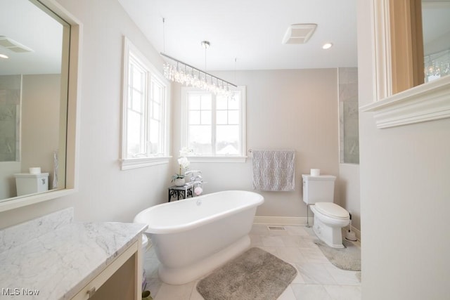 bathroom featuring a tub to relax in, tile patterned floors, vanity, an inviting chandelier, and toilet