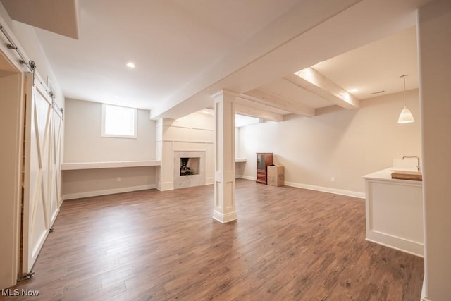 basement featuring a barn door, a premium fireplace, sink, and dark hardwood / wood-style floors