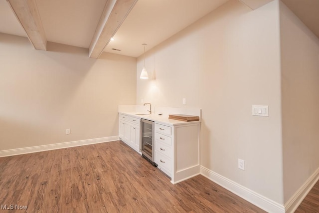 bar featuring pendant lighting, white cabinets, beam ceiling, wood-type flooring, and beverage cooler