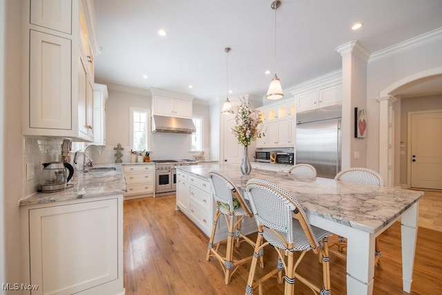 kitchen with decorative backsplash, high end appliances, a spacious island, decorative light fixtures, and white cabinets