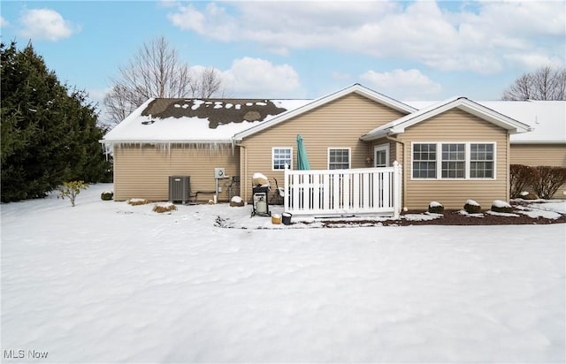 snow covered house with a wooden deck and central AC unit