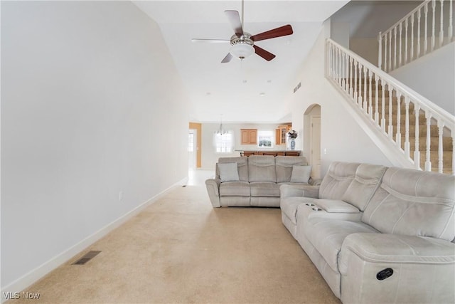 living room featuring light carpet, ceiling fan with notable chandelier, and lofted ceiling