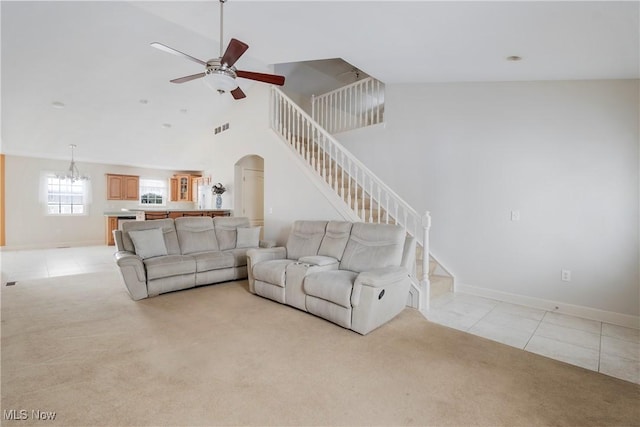 tiled living room with high vaulted ceiling and ceiling fan with notable chandelier