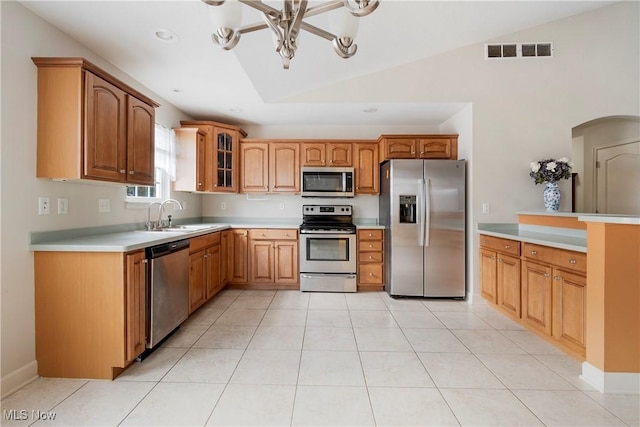 kitchen featuring appliances with stainless steel finishes, vaulted ceiling, sink, light tile patterned floors, and an inviting chandelier