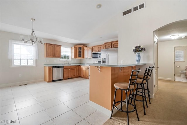 kitchen with a breakfast bar, an inviting chandelier, light tile patterned flooring, kitchen peninsula, and stainless steel appliances