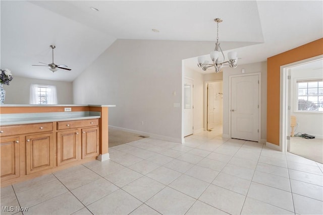 kitchen featuring vaulted ceiling, light tile patterned floors, pendant lighting, and ceiling fan with notable chandelier