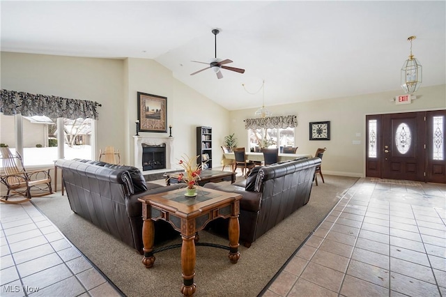 living room featuring ceiling fan with notable chandelier, vaulted ceiling, and light tile patterned flooring