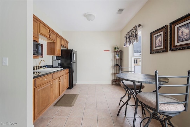 kitchen with black appliances, light tile patterned floors, and sink