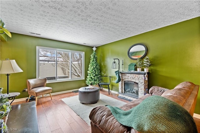 interior space with hardwood / wood-style flooring, a stone fireplace, and a textured ceiling