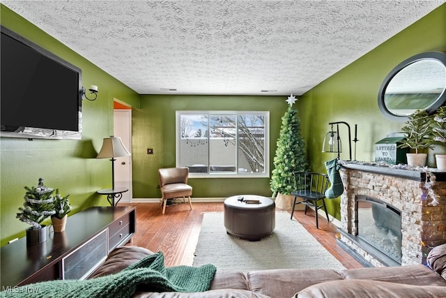 living room featuring a fireplace, wood-type flooring, and a textured ceiling