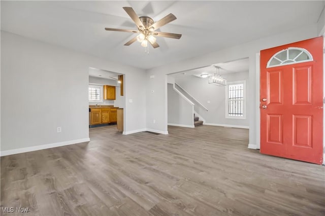 unfurnished living room with wood-type flooring, sink, and ceiling fan with notable chandelier