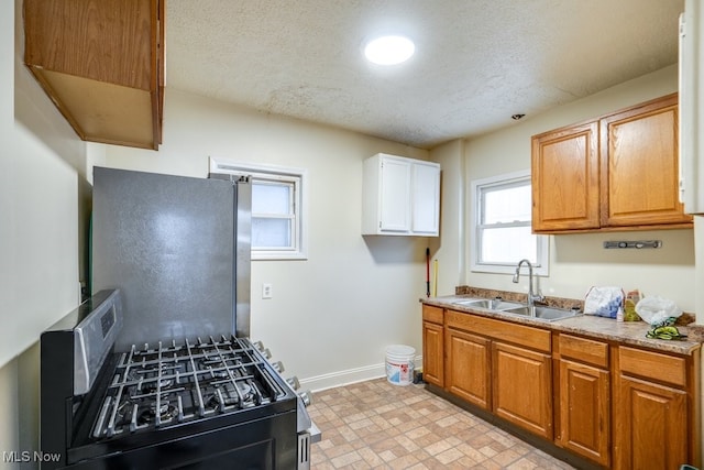 kitchen with stainless steel fridge, a textured ceiling, black range with gas cooktop, and sink