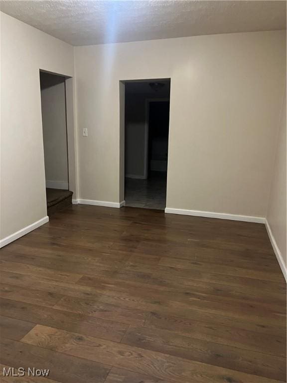 spare room featuring dark hardwood / wood-style floors and a textured ceiling