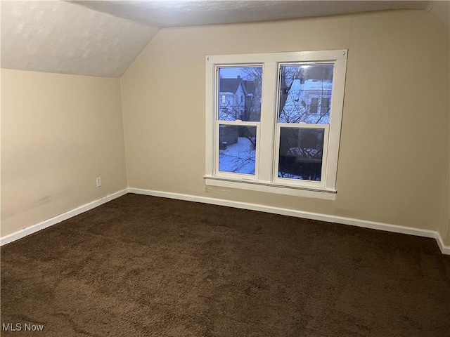 additional living space featuring dark carpet and vaulted ceiling