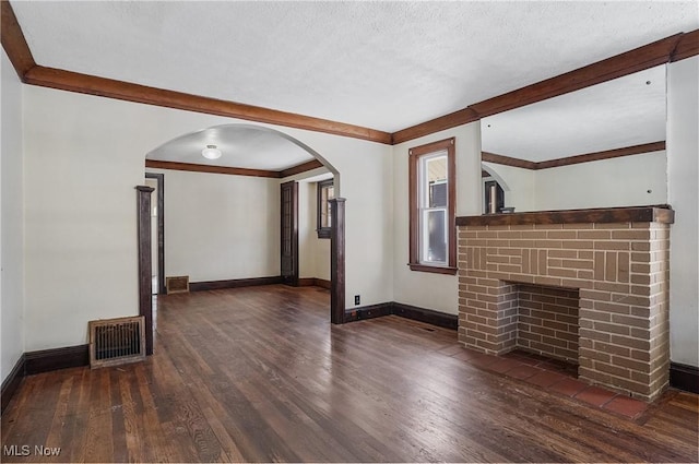 unfurnished living room featuring crown molding, a fireplace, dark wood-type flooring, and a textured ceiling