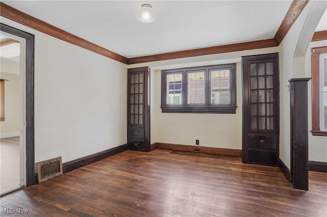 empty room with crown molding and dark wood-type flooring