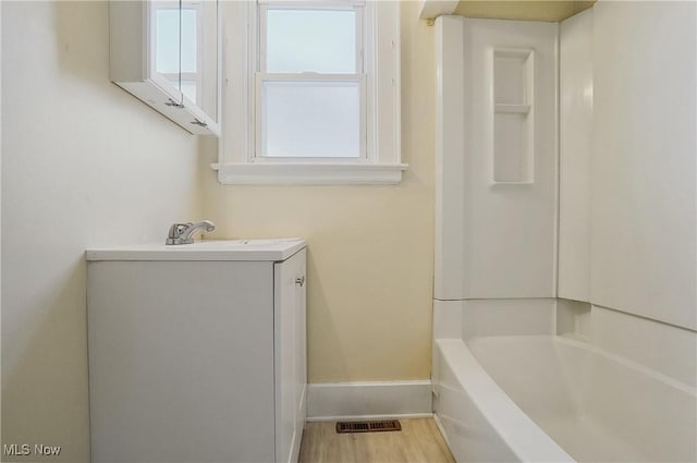 bathroom with hardwood / wood-style floors, vanity, and a tub