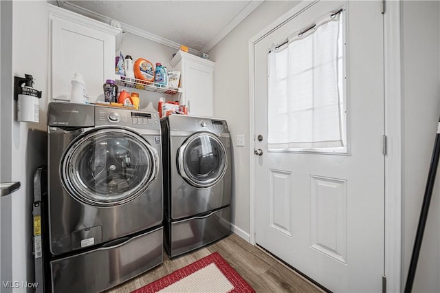 laundry room with light hardwood / wood-style flooring, cabinets, crown molding, and washing machine and clothes dryer