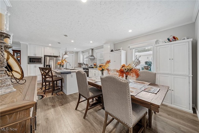 dining area featuring hardwood / wood-style floors, a textured ceiling, crown molding, and sink