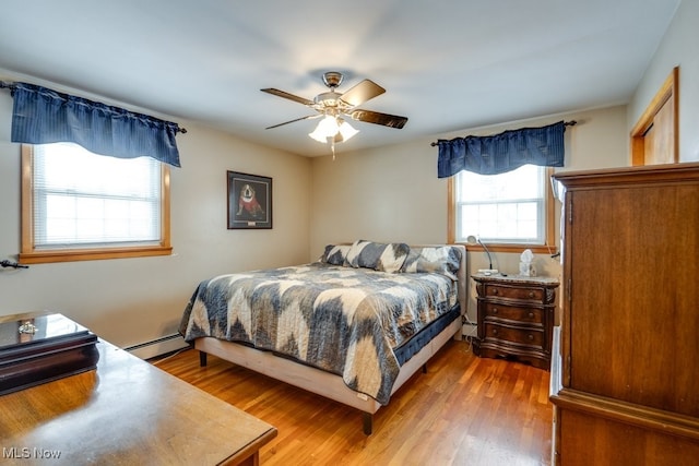 bedroom featuring ceiling fan, baseboard heating, and wood finished floors