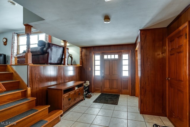 entryway with light tile patterned flooring, stairway, and wood walls