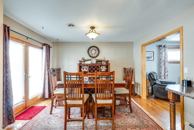 dining room featuring light wood-type flooring, a baseboard heating unit, and visible vents