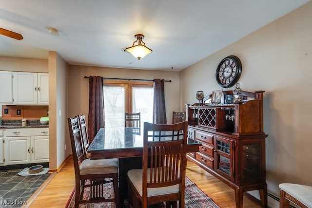 dining area featuring wood finished floors, baseboards, and a baseboard radiator