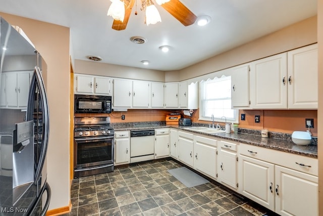 kitchen featuring dark countertops, visible vents, stainless steel appliances, white cabinetry, and a sink