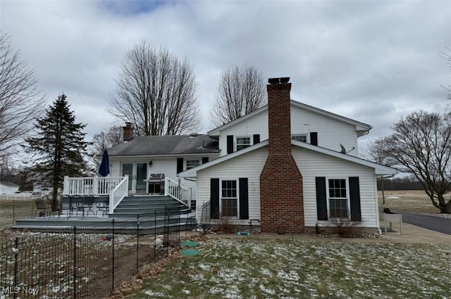 back of house featuring a wooden deck, a chimney, and fence