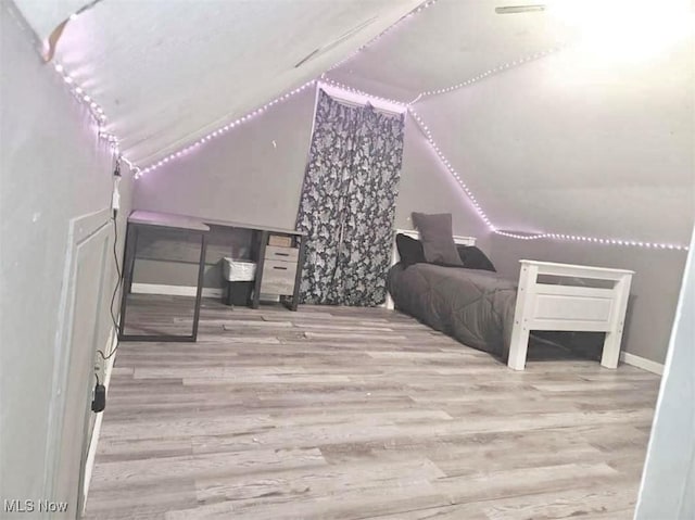 bedroom featuring light wood-type flooring and vaulted ceiling