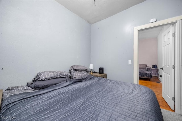 bedroom with hardwood / wood-style flooring and lofted ceiling