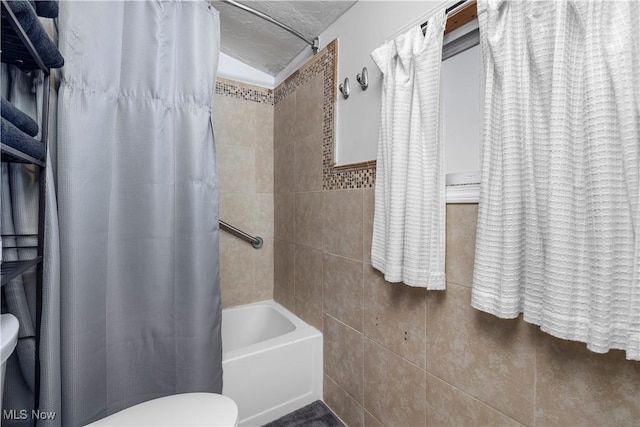 bathroom with tile walls, toilet, and shower / bath combo