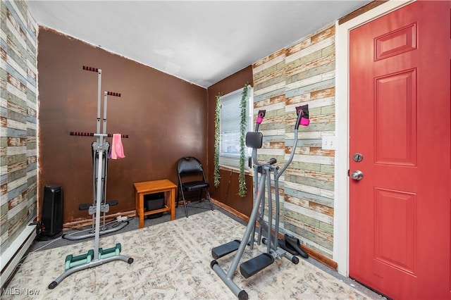 workout room with a baseboard radiator and wood walls