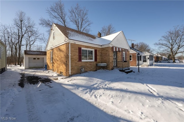 view of snowy exterior with an outbuilding and a garage