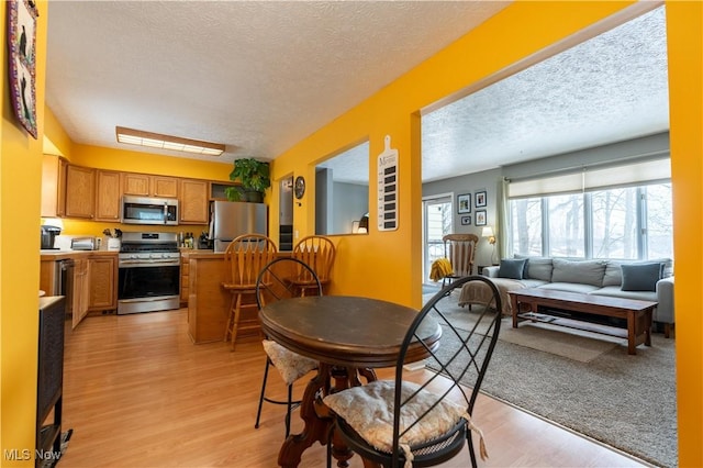 dining area with a textured ceiling and light hardwood / wood-style floors