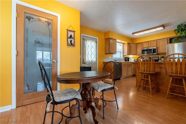 dining area featuring light hardwood / wood-style flooring and a textured ceiling