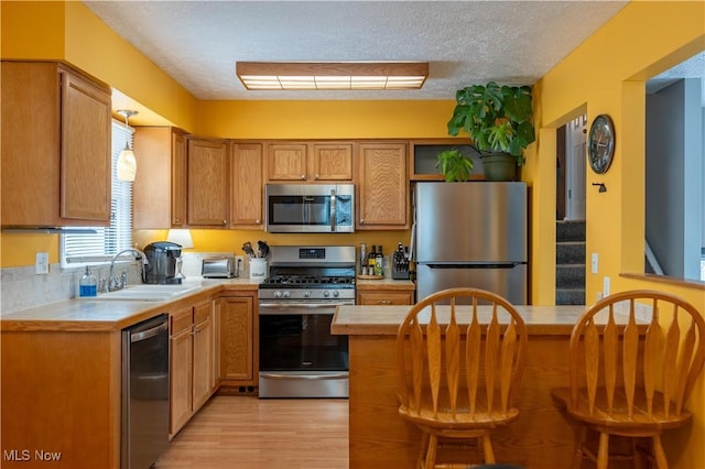 kitchen featuring appliances with stainless steel finishes, a textured ceiling, a breakfast bar area, and sink