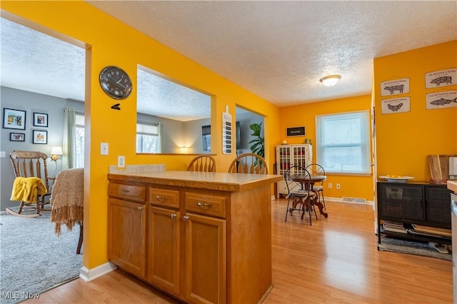 kitchen featuring kitchen peninsula, a textured ceiling, and light hardwood / wood-style flooring