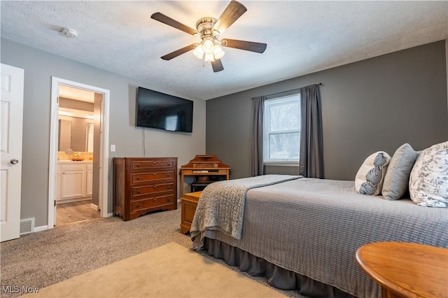 carpeted bedroom featuring a textured ceiling, ensuite bathroom, and ceiling fan