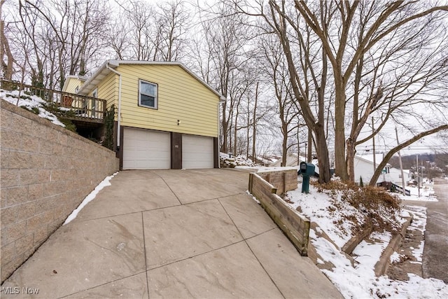 snow covered property featuring a garage and a wooden deck