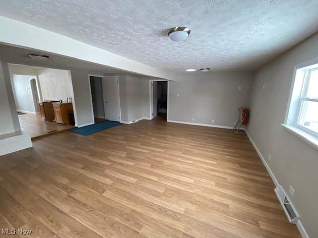 unfurnished room with a textured ceiling and light hardwood / wood-style floors