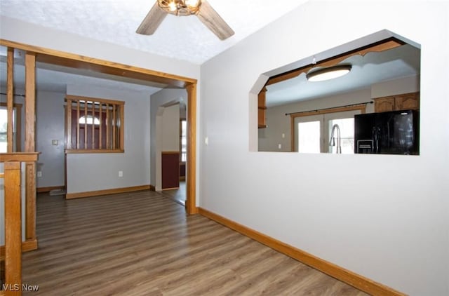 interior space with a ceiling fan, a sink, baseboards, and wood finished floors