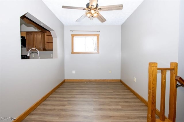 unfurnished room featuring light wood-style flooring, baseboards, and a sink