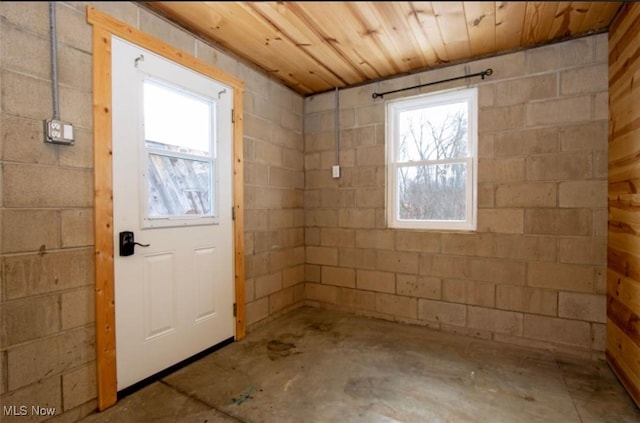 doorway to outside with concrete flooring, wooden ceiling, and concrete block wall