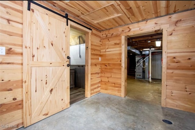 empty room with a barn door, unfinished concrete floors, wood ceiling, and wooden walls