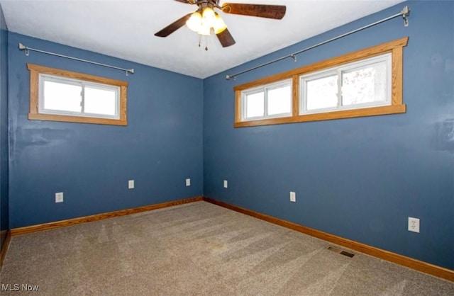 carpeted empty room with baseboards, visible vents, and a healthy amount of sunlight