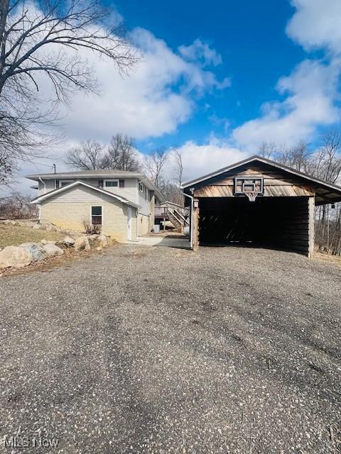 view of side of property featuring gravel driveway and an outdoor structure