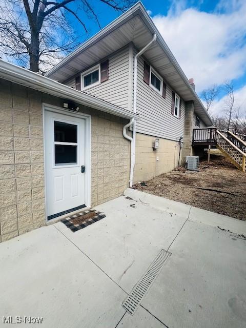 view of home's exterior featuring a patio area, concrete block siding, and cooling unit